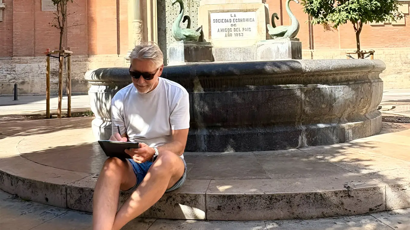 Rino Larsen sitter med en skisseblokk ved en fontene i Valencia.