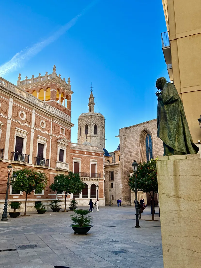 Vakker arkitektur rundt et torg i Valencia, med en gammel kirke i bakgrunnen.