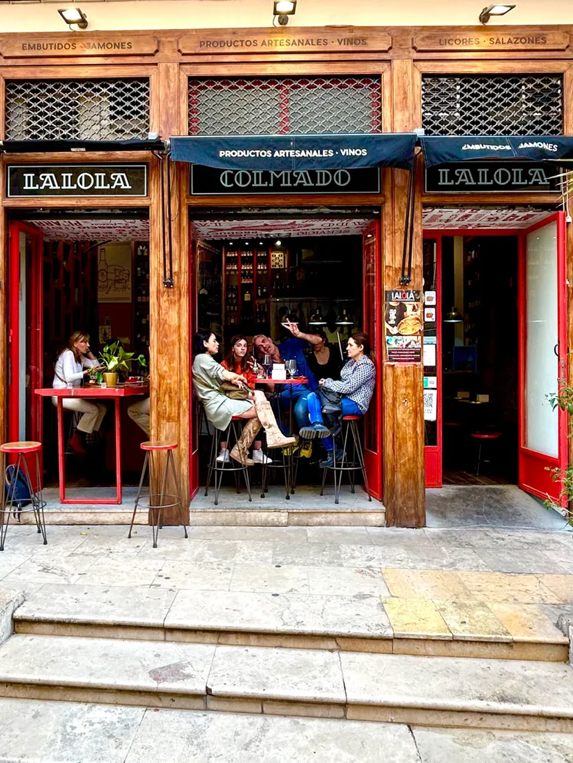 En vinbar i Valencia med åpne vinduer fra gulv til tak, og gjester som koser seg. 