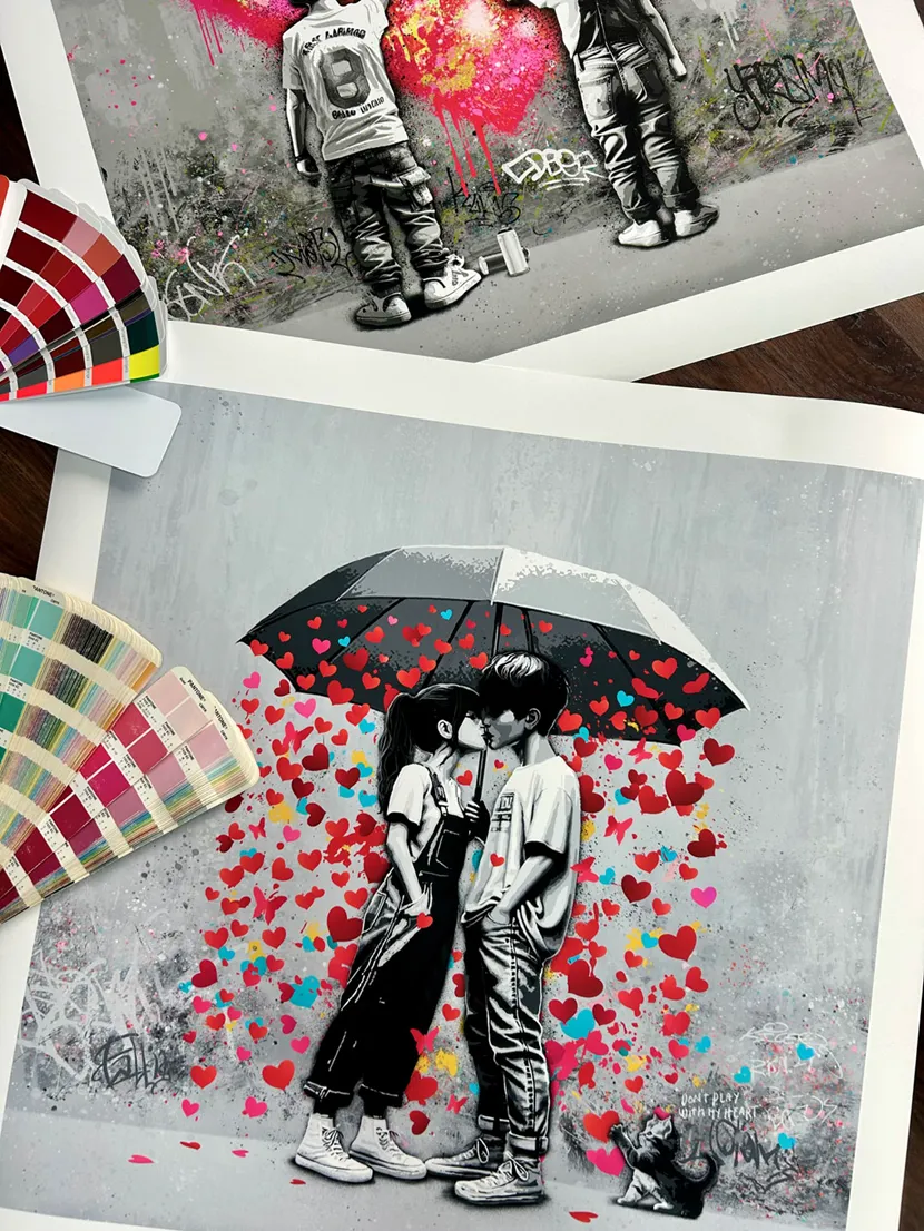 Trykkene Falling og Forever U ligger på et bord sammen med fargevifter.