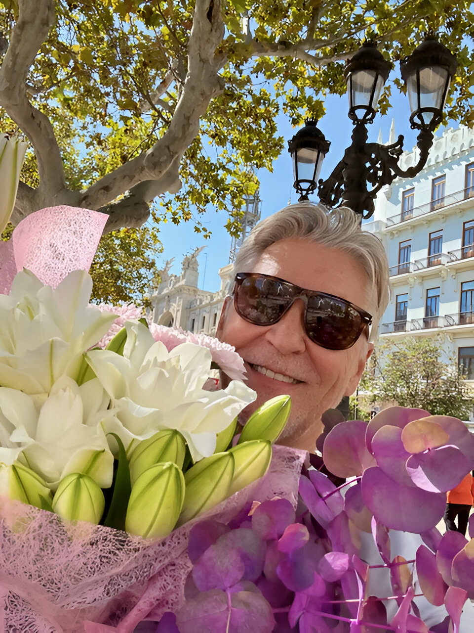 Rino Larsen titter opp bak en fargerik blomsterbukett.