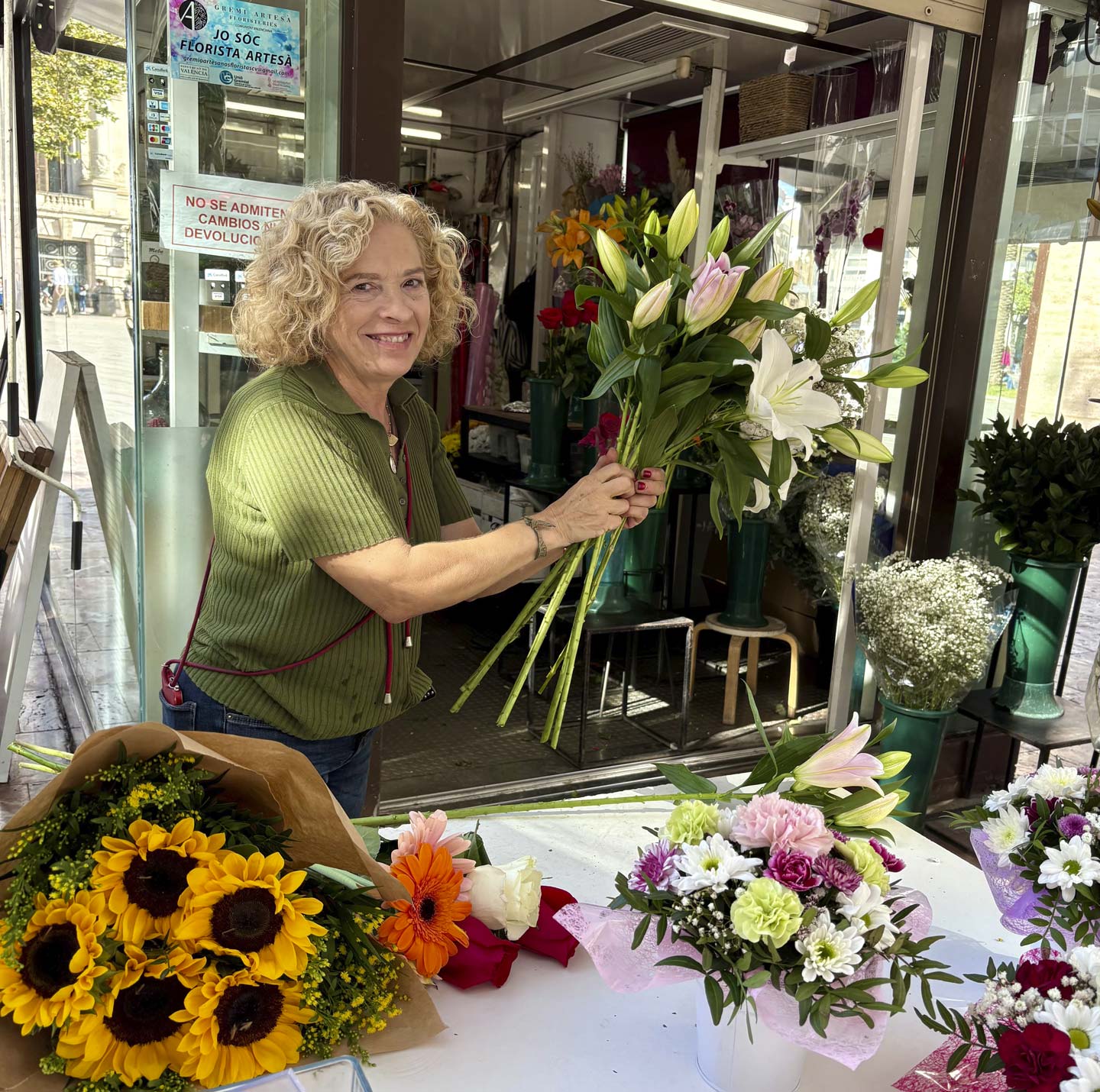 Mebe smiler mens hun setter sammen en blomstrebukett.